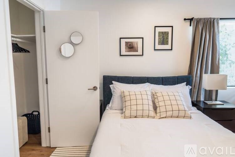 A bedroom with a bed, two pillows, a lamp, and a picture on the wall.