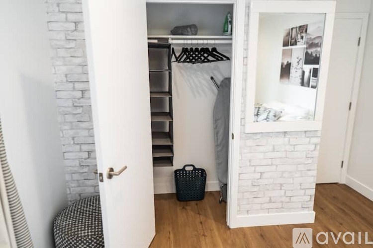 A white closet with a mirror and a black bag on the floor.