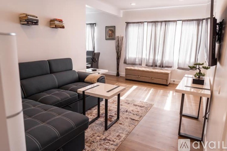 A living room with a black sofa and a glass table.