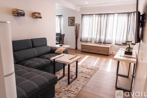 A living room with a black sofa and a glass table.