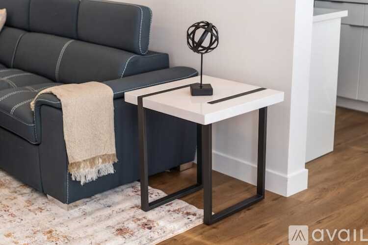 A black leather sofa with a white throw blanket draped over it.