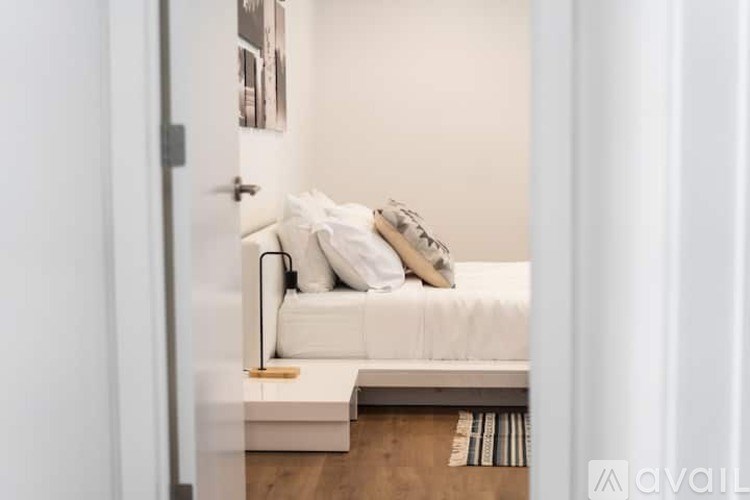 A white bed with a white headboard and pillows in a room.