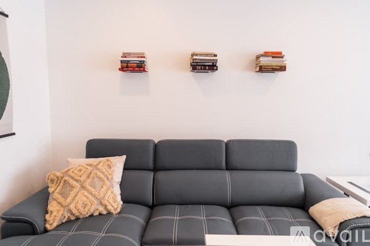 A black sofa with a tan pillow and a grey pillow on it.