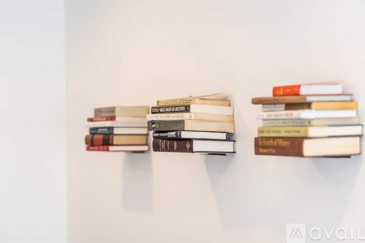 A white wall with three shelves of books.
