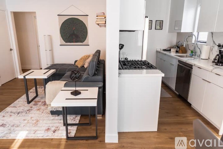 A kitchen with a white fridge and a black sofa with a white table in front of it.