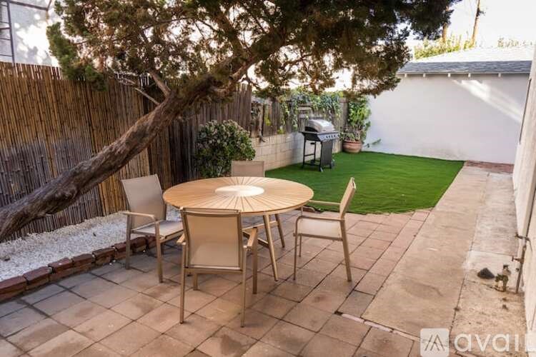 A patio with a table and chairs under a tree.