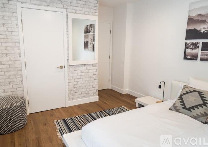 A bedroom with a white bed, a white door, and a white wall.