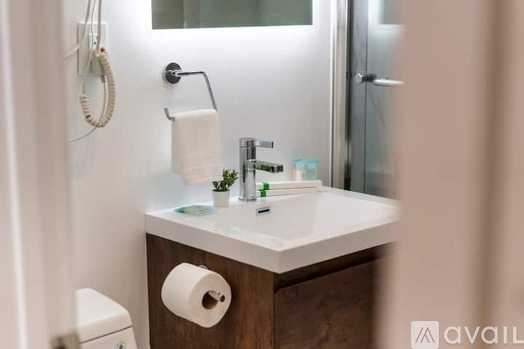 A bathroom with a white sink and a toilet paper roll on the counter.