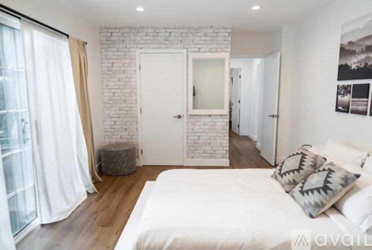 A bedroom with a white bed and a white brick wall.