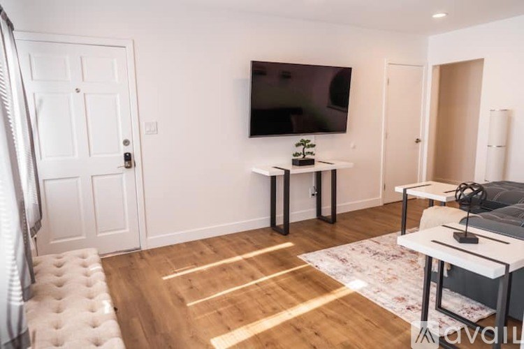 A living room with a flat screen TV mounted on the wall and a white sofa.