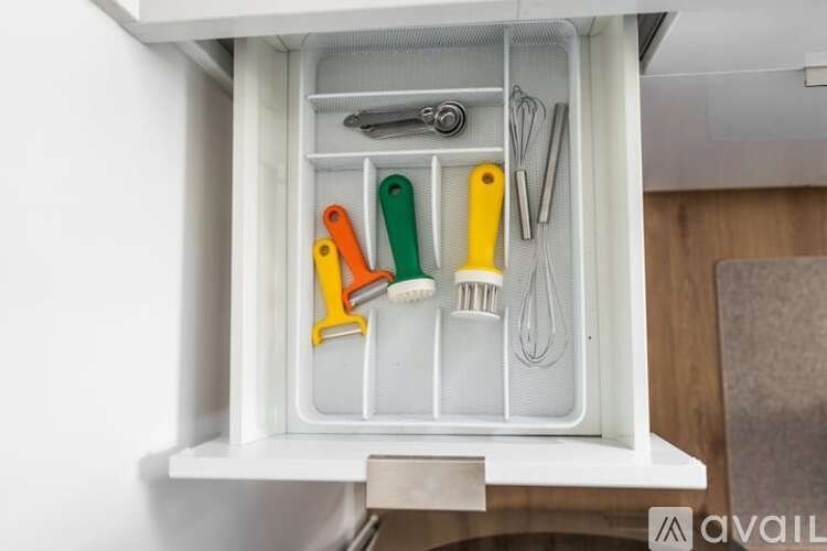 A drawer with utensils and a whisk in it.