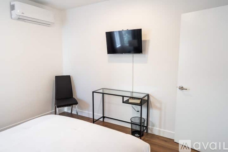 A black chair sits in front of a white bed.