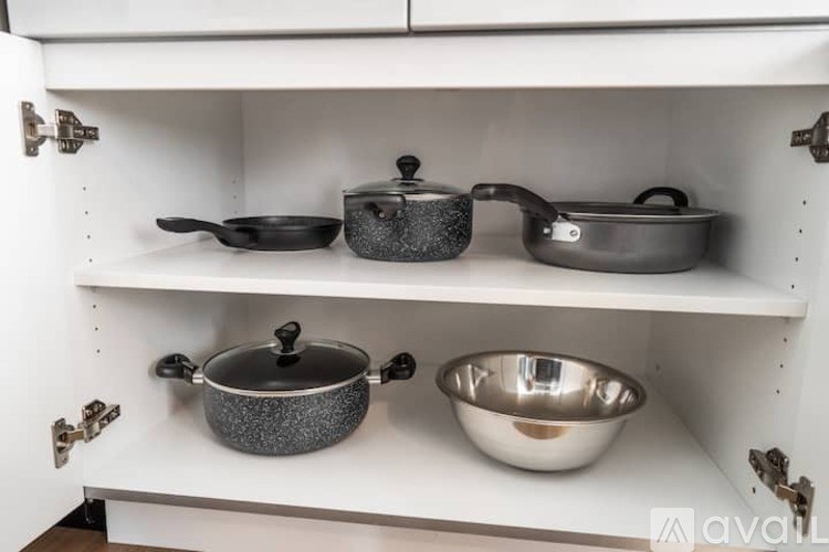 A set of pots and pans are on a white shelf.