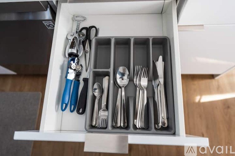 A drawer with utensils and a pair of scissors.