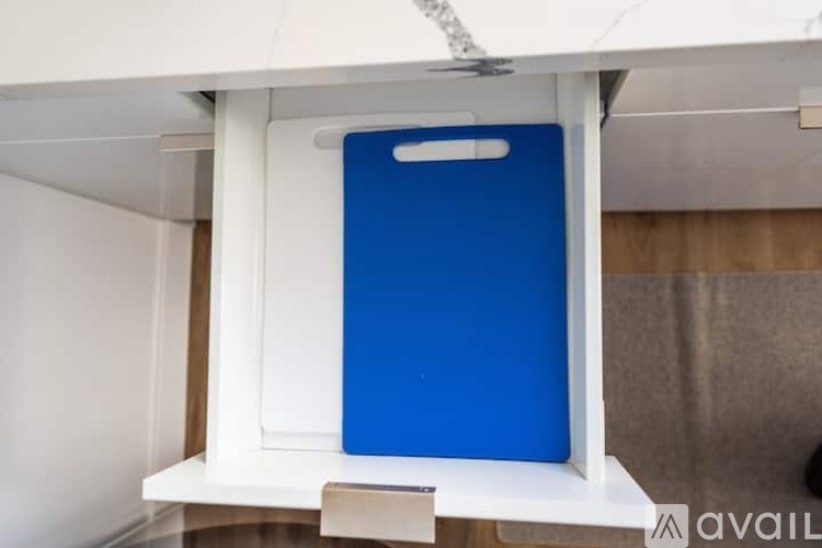 A blue framed mirror on a white shelf.