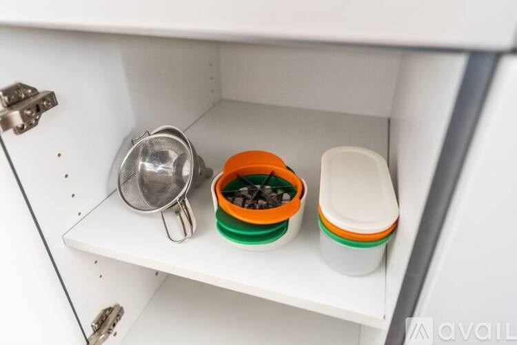 A white drawer with a silver container, a green container with chocolate chips, and a white container with a green lid.