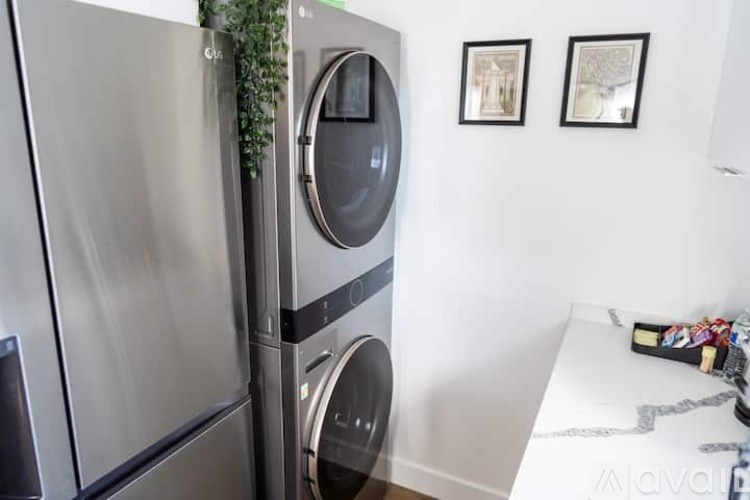 A modern kitchen with a stainless steel refrigerator and a washing machine.