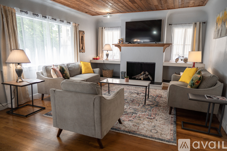 A living room with a grey couch, a fireplace, and a television.