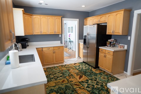 A kitchen with wooden cabinets and a black refrigerator.