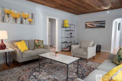 A living room with a grey couch, a white coffee table, and a rug with a pattern of red, blue, and yellow.