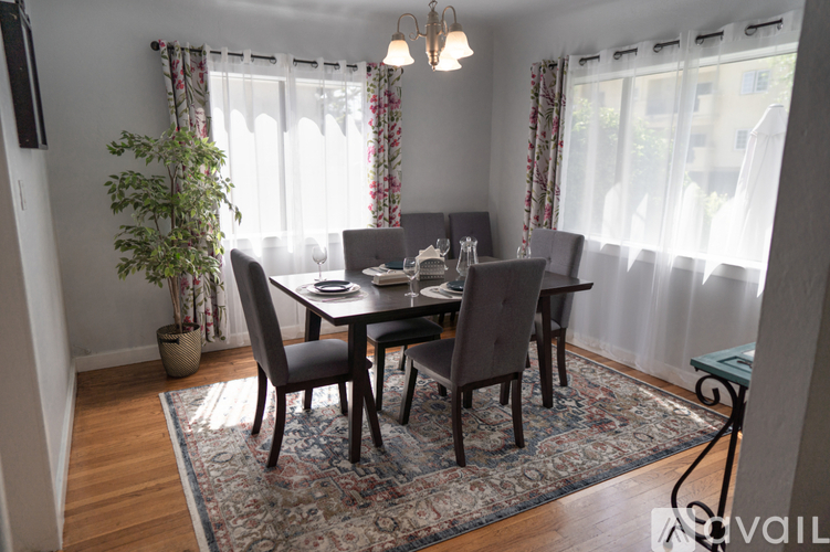 A dining room with a table set for four and a potted plant.