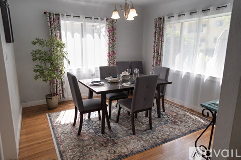 A dining room with a table set for four and a potted plant.