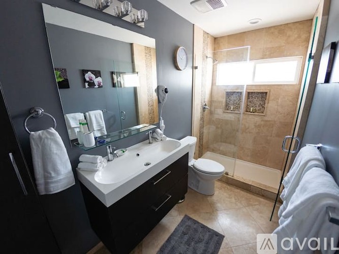 A bathroom with a white sink, toilet, and a glass shower stall.