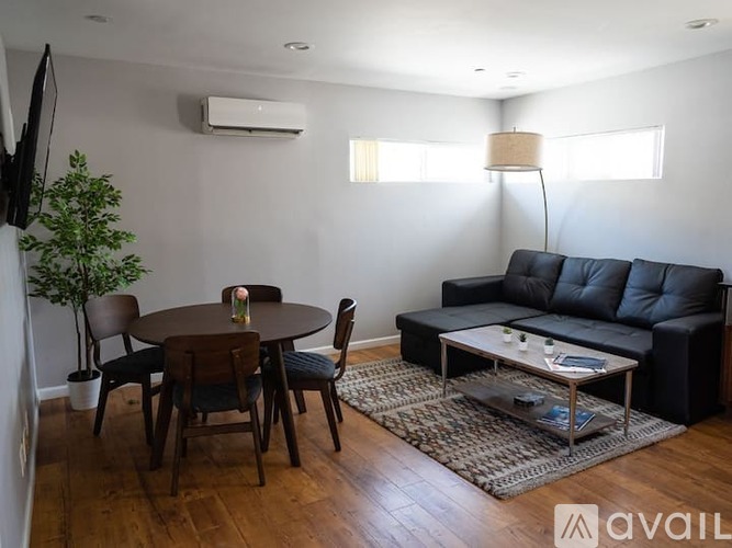 A living room with a black couch, a wooden table, and a glass coffee table.