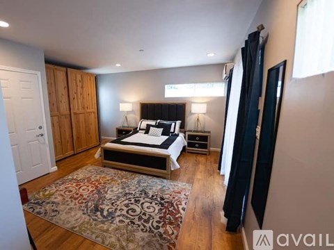 A bedroom with a large bed and a rug on the floor.