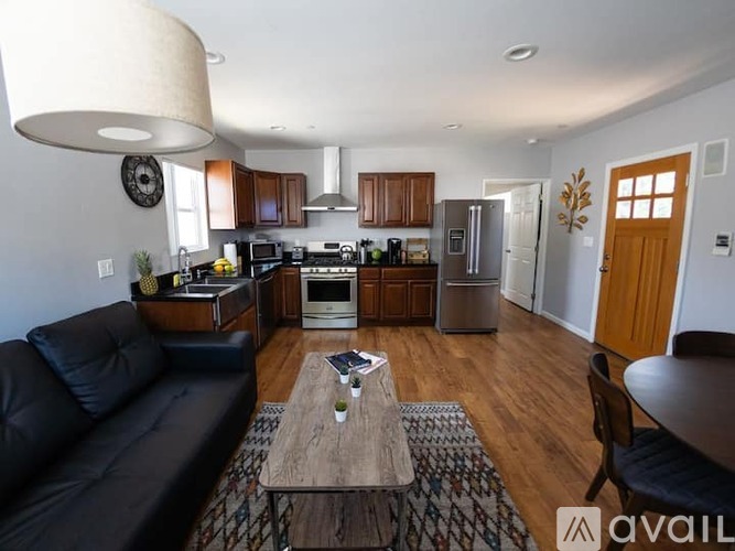 A modern kitchen with a black couch and wooden floors.