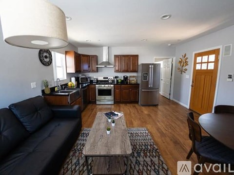 A modern kitchen with a black couch and wooden floors.