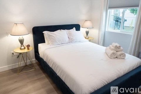 A bedroom with a large bed, two lamps, and a small table with a lamp on it.