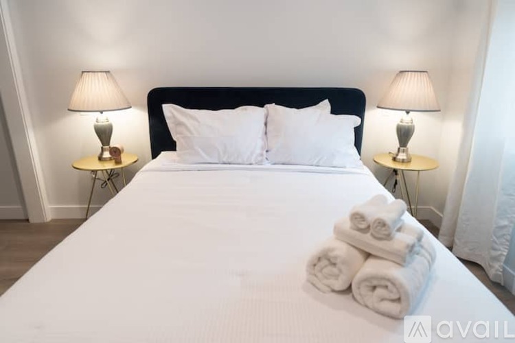 A bed with white bedding and towels on top of it.