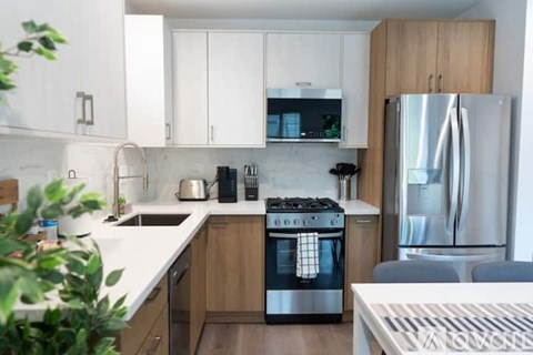 A modern kitchen with a stainless steel refrigerator and wooden cabinets.