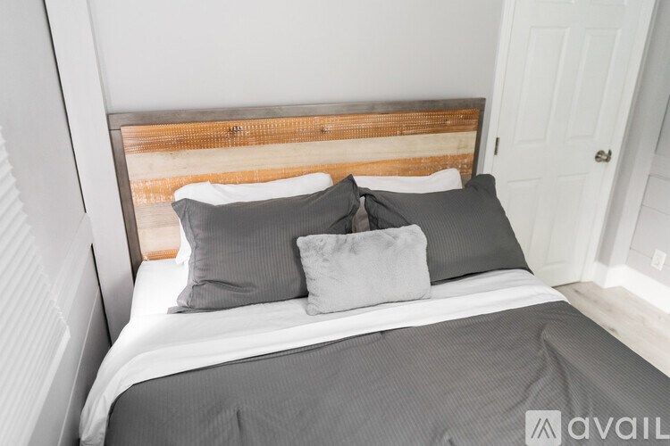 A bed with a wooden headboard and two grey pillows.
