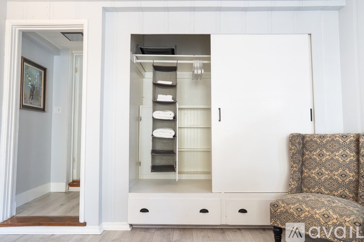 A white cabinet with drawers and shelves is open in a room.