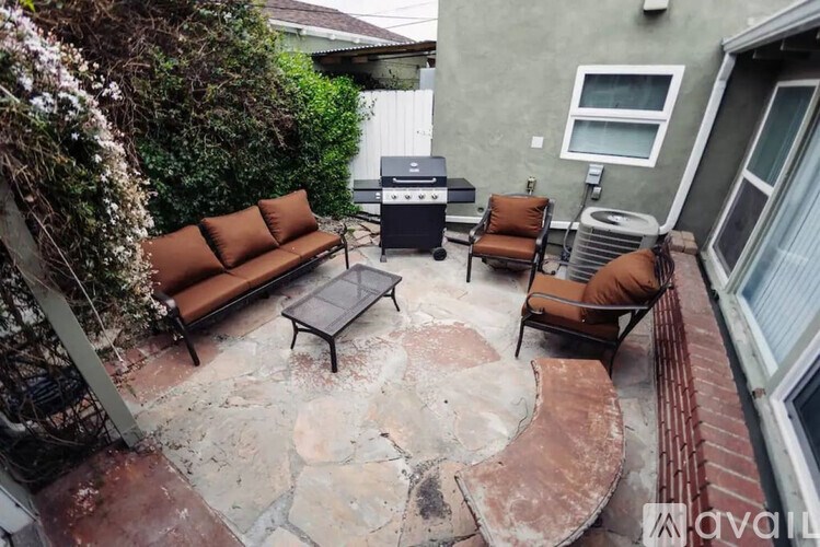 A patio with a table, chairs, and a grill.