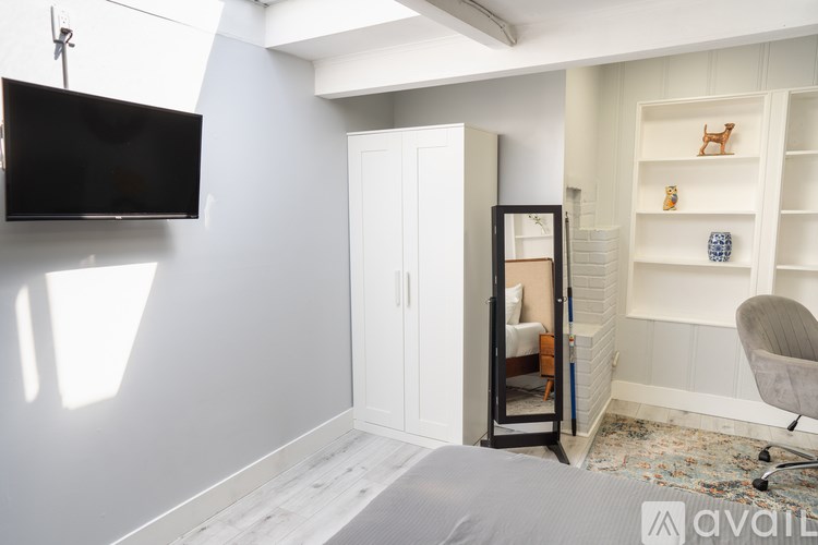 A room with a grey bed and a white chair.