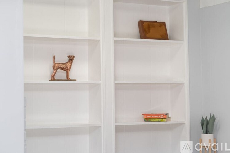 A shelf with a dog figurine, a book, and a plant.