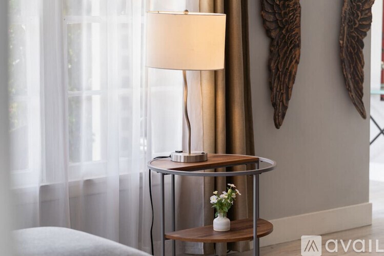 A table with a lamp and a vase with flowers on it.