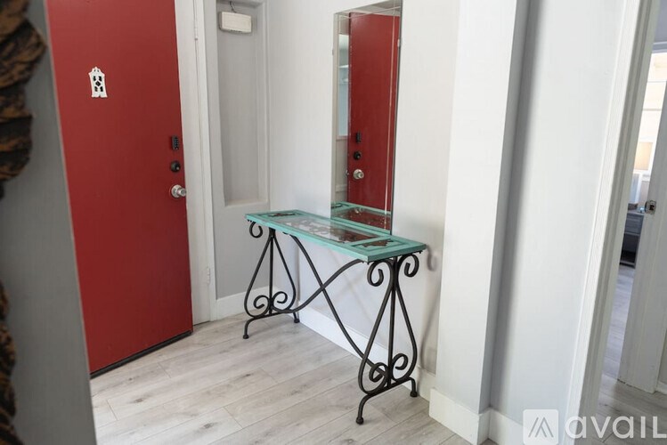 A glass top table with metal legs sits in a hallway.