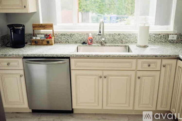 A kitchen with a stainless steel dishwasher and white cabinets.