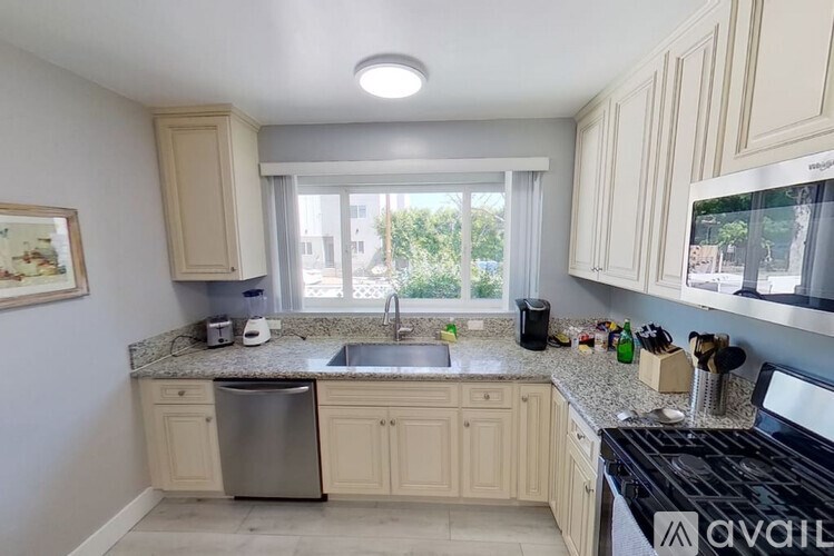 A kitchen with a sink, stove, and cabinets.