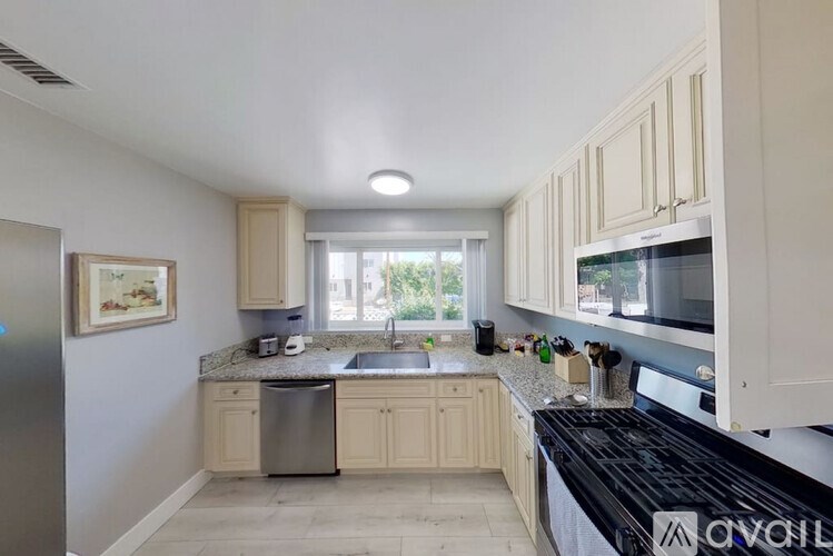 A kitchen with white cabinets and a black countertop.
