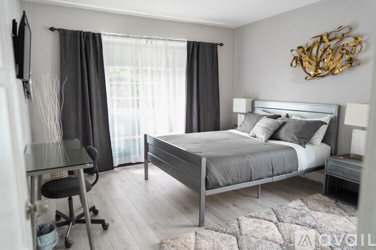 A bedroom with a bed, chair, and a wall decoration.