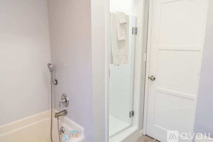 A white door is open to a bathroom with a white tub and shower.