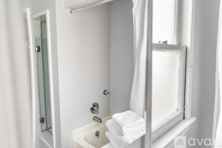 A white bathroom with a tub, shower, and window.