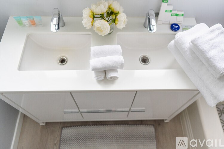 A white sink with a bouquet of white flowers and towels on top.