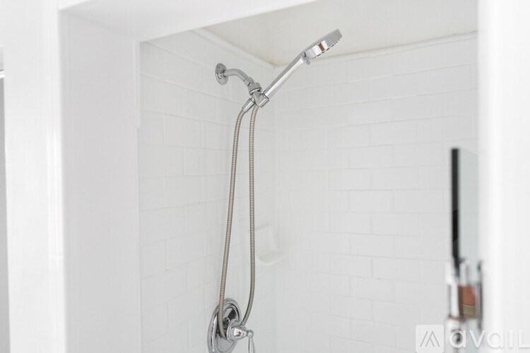 A white bathroom with a shower head and hand shower.