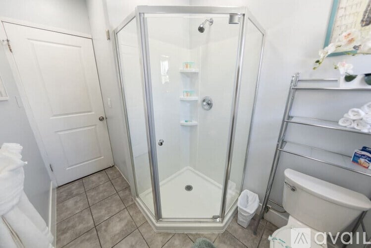 A bathroom with a glass shower stall and a toilet.